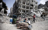 Palestinians sit by their belongings after visiting buildings destroyed in Khan Younis, Gaza Strip, March 6, 2024. (Mohammed Dahman/AP)