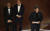 James Wilson, from left, Leonard Blavatnik, and Jonathan Glazer accept the award for 'The Zone of Interest' for best international feature film during the Oscars, at the Dolby Theatre in Los Angeles, March 10, 2024. Glazer, in his acceptance speech, denounced Israel’s occupation of Palestinian territory, which he said had led to “dehumanization” that had affected both Israelis and Palestinians. (Chris Pizzello/AP)