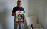 Nissan Kalderon poses with a photo of his only brother, Ofer, a hostage held in the Gaza Strip by the Hamas terror group, in Ramat Gan, March 13, 2024 (AP Photo/Ariel Schalit)