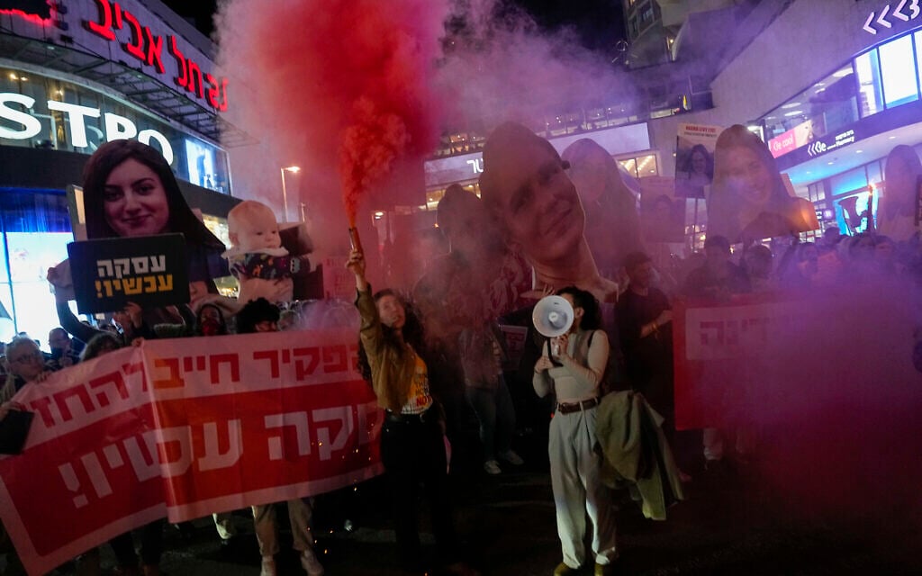 Activists block a road and light flares while holding photos depicting the faces of Israeli women who are being held hostage in the Gaza Strip, during a protest demanding their release from Hamas captivity, in Tel Aviv on March 14, 2024. (AP Photo/Ariel Schalit)