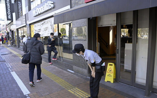 A McDonald's employee bows in front of its store amid the company's system outages in Tokyo, Friday, March 15, 2024. Reports of system outages at McDonald's are growing around the world, shuttering restaurants and leading to social media complaints. M(Kyodo News via AP)