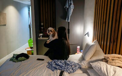 Maya Elharar, evacuated with her family from Kiryat Shmona, holds her dog in her hotel room in Tiberias, northern Israel, March 4, 2024. (AP Photo/Ariel Schalit)