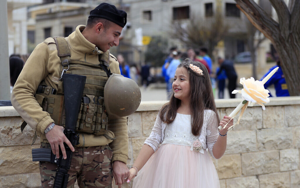 A Lebanese army soldier speaks with a girl as he stands guard outside a church during the traditional Palm Sunday procession in the southern village of Rmeish, a Lebanese border village with Israel, Sunday, March 24, 2024. (AP Photo/Mohammed Zaatari, File)