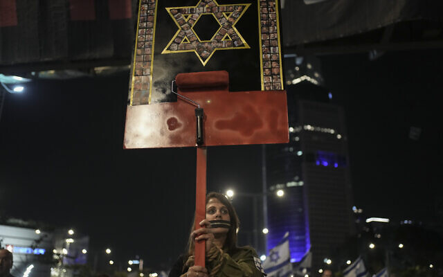 A woman holds up a sign with images of hostages held captive by Hamas in the Gaza Strip as she attends a rally calling for their release in Tel Aviv, March 30, 2024. (AP Photo/Maya Alleruzzo)