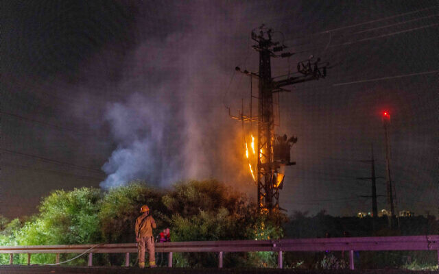 Firefighters try to put out a blaze on an electricity pylon in central Israel after it was hit by a rocket fired from Gaza, October 26, 2023. (Yossi Aloni/Flash90)
