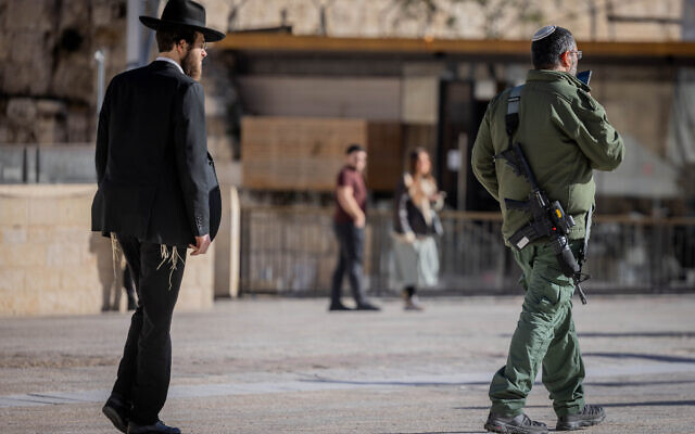 A reserves soldier, right, walks next to an ultra-Orthodox Jewish man in the Old City of Jerusalem, January 10, 2024. (Chaim Goldberg/Flash90) A reserves soldier, right, walks next to an ultra-Orthodox Jewish man in the Old City of Jerusalem, January 10, 2024. (Chaim Goldberg/Flash90)