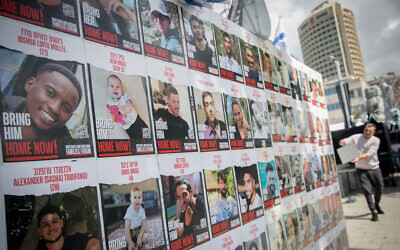 A man puts of photographs of the Israelis still held hostage by Hamas terrorists in Gaza, at 'Hostage Square' in Tel Aviv, March 4, 2024. (Miriam Alster/Flash90)