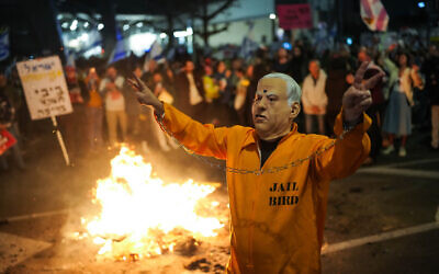 An anti-government demonstrator wearing a costume of Prime Minister Benjamin Netanyahu in a prison jumpsuit   protests outside the IDF's Kirya military headquarters in Tel Aviv on March 23, 2024. (Erik Marmor/Flash90)