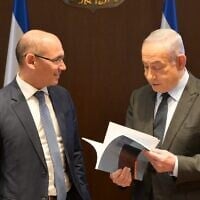 Bank of Israel chief Amir Yaron, left, gives Prime Minister Benjamin Netanyahu the central bank's year-end report in Jerusalem, March 28, 2024. (Amos Ben-Gershom/GPO)