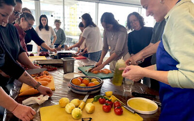 Musician and chef Adi Weinberg (right) cooks with evacuees from the Gaza border communities at Tel Aviv's Asif on March 17, 2024 (Jessica Steinberg/Times of Israel)