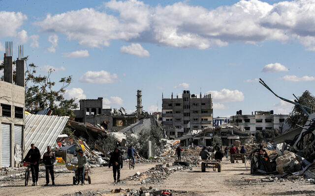 People walk past destroyed buildings in the Maghazi refugee camp in the central Gaza Strip on February 1, 2024. (Anas Baba/ AFP) People walk past destroyed buildings in the Maghazi refugee camp in the central Gaza Strip on February 1, 2024. (Anas Baba/ AFP)