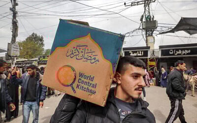 A man carries a cardboard box of food aid provided by World Central Kitchen in Rafah in the southern Gaza Strip on March 17, 2024. (Mohammed Abed/AFP)