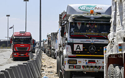 Illustrative - Egyptian trucks carrying humanitarian aid bound for the Gaza Strip queue outside the Egyptian side of the Rafah border crossing with the enclave, March 23, 2024. (Khaled Desouki/AFP)
