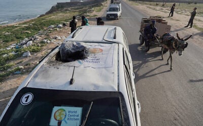 People gather around the car used by US-based aid group World Central Kitchen, that was hit by an Israeli strike the previous day in Deir al-Balah in the central Gaza Strip on April 2, 2024. (AFP)