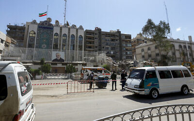 Vehicles drive past the cordoned-off Iranian Embassy building as workers remove the rubble of a consular annex a day after it was hit in a strike in Damascus, Syria, April 2, 2024. (Louai Beshara/AFP)