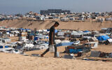 A Palestinian man ferries water at a makeshift camp for displaced people in Rafah in the southern Gaza Strip on April 4, 2024. (Mohammed Abed/AFP)