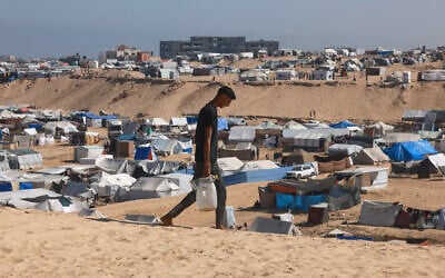 A Palestinian man ferries water at a makeshift camp for displaced people in Rafah in the southern Gaza Strip on April 4, 2024. (Mohammed Abed/AFP)