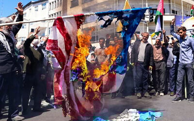Illustrative: Demonstrators burn a US and an Israeli flag during the funeral for seven Islamic Revolutionary Guard Corps members killed in a strike in Syria, which Iran blamed on Israel, in Tehran on April 5, 2024. (Atta Kenare / AFP)