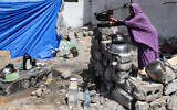 A woman washes pots outside a tent pitched by a destroyed building in Rafah in the southern Gaza Strip on April 5, 2024. (Mohammed Abed / AFP)