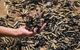 A person holds a handful of spent bullet casings above a bigger pile in Khan Younis on April 7, 2024, after Israel pulled its ground forces out of the southern Gaza Strip, six months into the war sparked by Hamas's October 7 attacks on southern Israel. (AFP)