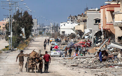 Men walk with an animal-drawn cart carrying salvaged wood from debris and trees past destroyed buildings in the southern Gaza city of Khan Younis on April 7, 2024. (AFP)