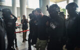 An Israeli man identified as Shalom Avitan (C) is escorted by Malaysian police upon his arrival at a court to face charges of possessing six handguns and 200 bullets in Kuala Lumpur on April 12, 2024. (Arif Kartono / AFP)