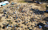 In this aerial view, visitors walk past portraits of people who were abducted or killed in the Hamas massacre at the Nova music festival on October 7, at the site of the festival near Kibbutz Reim in southern Israel, April 10, 2024. (Jack Guez / AFP)