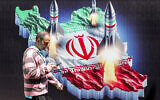 A man walks past a banner depicting missiles launching from a representation of the map of Iran colored with the Iranian flag in central Tehran on April 15, 2024. (Atta Kenare / AFP)