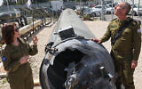 Israeli military spokesman Rear Admiral Daniel Hagari, right, and his deputy Masha Michelson pose next to an Iranian ballistic missile which was intercepted and fell into the Dead Sea days earlier, during a media tour at the Julis military base near the southern Israeli city of Kiryat Malachi on April 16, 2024. (Gil Cohen-Magen/AFP)