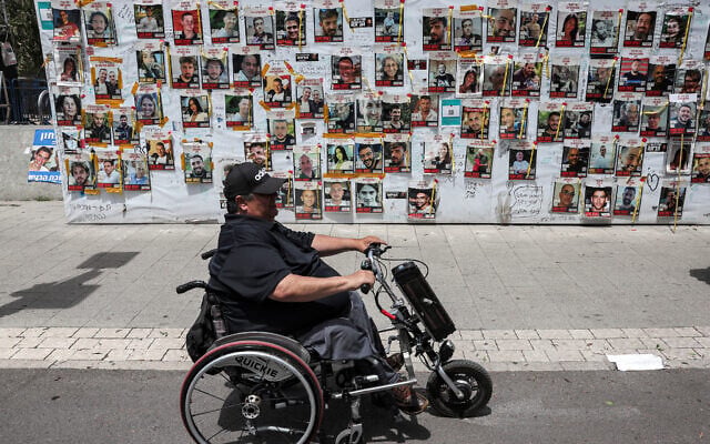 A person sitting in an electric wheelchair moves past posters of Israeli hostages held in Gaza by Hamas, in Tel Aviv on April 25, 2024. (Jack Guez/AFP) A person sitting in an electric wheelchair moves past posters of Israeli hostages held in Gaza by Hamas, in Tel Aviv on April 25, 2024. (Jack Guez/AFP)