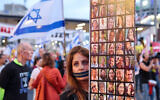 A protester with a zipper over her mouth holds a poster showing pictures of Israeli hostages taken captive by Hamas and other terrorists in Gaza during the October 7 attacks, during a demonstration calling for their release in Tel Aviv on April 27, 2024. (Jack Guez/AFP)
