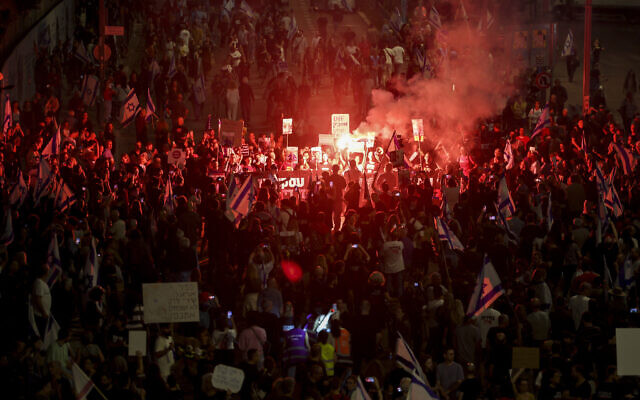 Relatives and supporters of hostages held captive by Hamas terrorists light flares and wave national flags during a demonstration calling for their release, in Tel Aviv on April 27, 2024. (JACK GUEZ / AFP)
