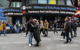 People walk around Times Square as news tickers display news about the earthquake on Friday April 5, 2024 in New York.  (AP Photo/Brittainy Newman)