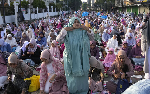 A Muslim woman dons her praying robe as she attends an Eid al-Fitr prayer marking the end of the holy fasting month of Ramadan in Jakarta, Indonesia, April 10, 2024. (Dita Alangkara/AP)