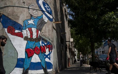 A man walks past a mural depicting the US President Joe Biden as a superhero defending Israel on a street in Tel Aviv, April 14, 2024. (AP Photo/Leo Correa)