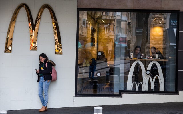 File: A woman standing under a McDonald's sign, in central Jerusalem, February 2, 2023. (Nati Shohat/Flash90) File: A woman standing under a McDonald's sign, in central Jerusalem, February 2, 2023. (Nati Shohat/Flash90)