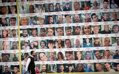 People walk by photographs of Israeli civilians held hostage by Hamas terrorists in Gaza, in Tel Aviv, April 9, 2023. (Miriam Alster/Flash90)