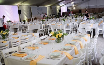 Members of Kibbutz Be'eri set up tables for the Seder on the first night of Passover, at Hostages Square in Tel Aviv. April 22, 2024. The kibbutz was among the worst hit in Hamas's October 7 massacre, and its residents have not been able to return. (Avshalom Sassoni/Flash90)
