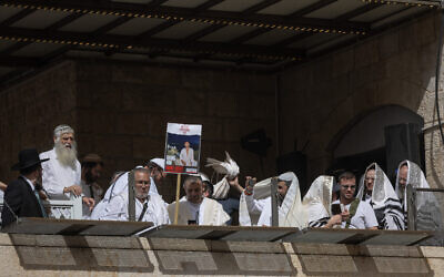 Father of Hamas-held hostage Eliya Cohen holds sign with his missing son's photo as he attends the Passover priestly blessing at the Western Wall in Jerusalem's Old City on April 25, 2024. (Chaim Goldberg/Flash90)