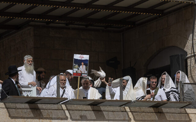 Father of Hamas-held hostage Eliya Cohen holds sign with his missing son's photo as he attends the Passover priestly blessing at the Western Wall in Jerusalem's Old City on April 25, 2024. (Chaim Goldberg/Flash90)