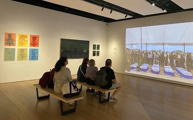 Visitors to Anu Museum of the Jewish People on March 27, 2024 watching the documentary portion of the 'October Seventh' exhibit. (Jessica Steinberg/Times of Israel)