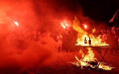 Protesters set fire to a "non-Seder" table outside Prime Minister Benjamin Netanyahu's residence in Caesarea call for a hostage release deal, April 24, 2024. (Arielle Skladman/Pro-Democracy Movement)