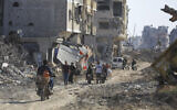 Palestinians walk through the destruction left by the Israeli air and ground offensive after the IDF withdrew from Khan Younis, southern Gaza Strip, April 7, 2024. (AP Photo/ Ismael Abu Dayyah)