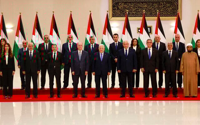 Palestinian Authority President Mahmoud Abbas poses for a picture with his new government, after it was sworn in on March 31, 2024, in Ramallah, in the West Bank. Finance Minister Omar Bitar is standing third from the left in the front row. (Jaafar ASHTIYEH / AFP)