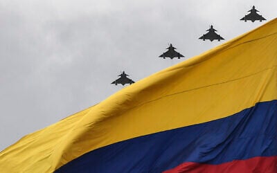 Kfir aircraft of the Colombian Air Force overfly a Colombian flag during a ceremony commemorating Colombia's Independence Day in Bogota on July 20, 2021. (Photo by Juan BARRETO / AFP)