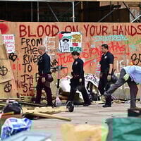 Police patrol as workers clean up anti-Israel graffiti at the University of California, Los Angeles (UCLA) campus after police evicted pro-Palestinian protesters, May 2, 2024. (Frederic J. Brown/AFP)