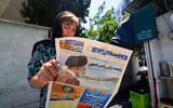 A woman reads a newspaper with a front-page report on the crash of the Iranian president's helicopter outside a kiosk in Tehran on May 20, 2024. (Atta Kenare / AFP)