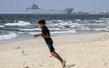 A child plays on a beach as a ship transporting international humanitarian aid is moored at the US-built Trident Pier near Nuseirat in the central Gaza Strip on May 21, 2024, amid the ongoing conflict between Israel and the Palestinian terror Hamas group. (AFP)