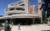 A man walks outside the West Bank Ramallah municipality building on May 24, 2024, adorned with flags of Spain, Ireland and Norway. (Ahmad Gharabli/ AFP)