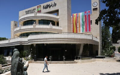 A man walks outside the West Bank Ramallah municipality building on May 24, 2024, adorned with flags of Spain, Ireland and Norway. (Ahmad Gharabli/ AFP)